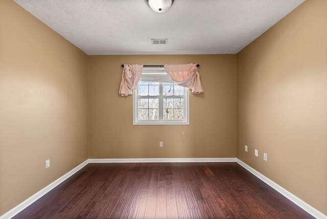 spare room featuring a textured ceiling and dark hardwood / wood-style flooring