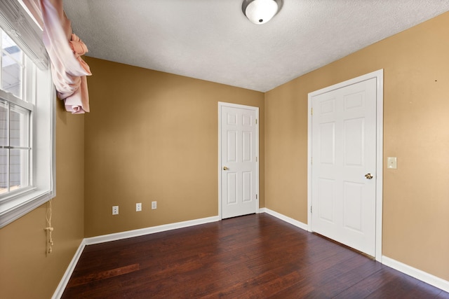 unfurnished bedroom with dark hardwood / wood-style flooring and a textured ceiling