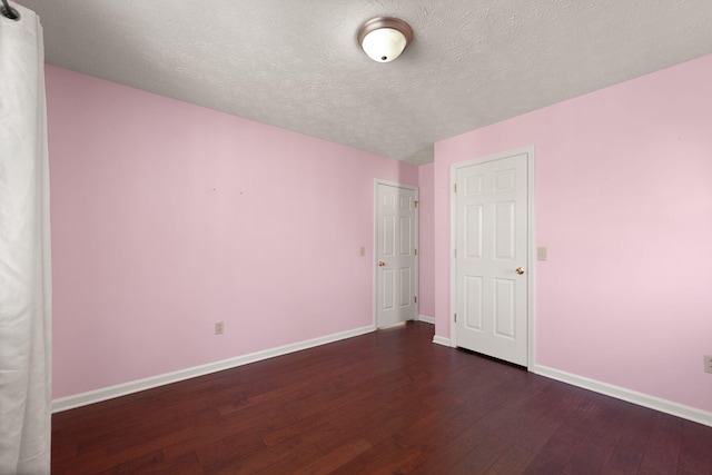 unfurnished bedroom featuring dark wood-type flooring and a textured ceiling