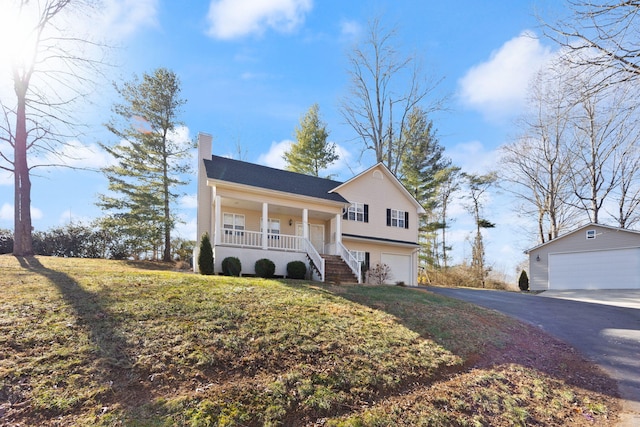 view of front of home with a chimney, a front lawn, aphalt driveway, a garage, and covered porch