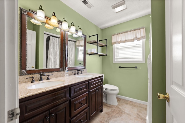 bathroom with tile patterned flooring, vanity, a textured ceiling, and toilet