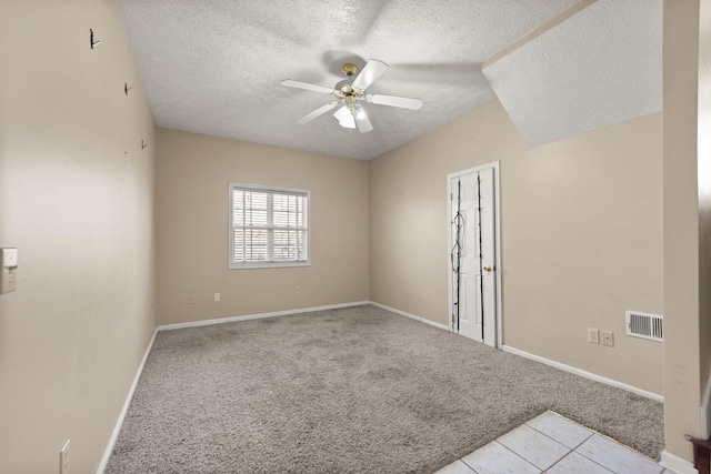 spare room featuring ceiling fan, light carpet, and a textured ceiling