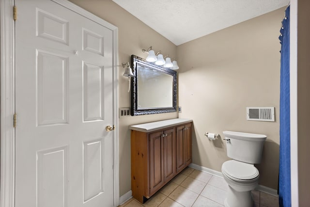 bathroom with tile patterned flooring, vanity, a textured ceiling, and toilet