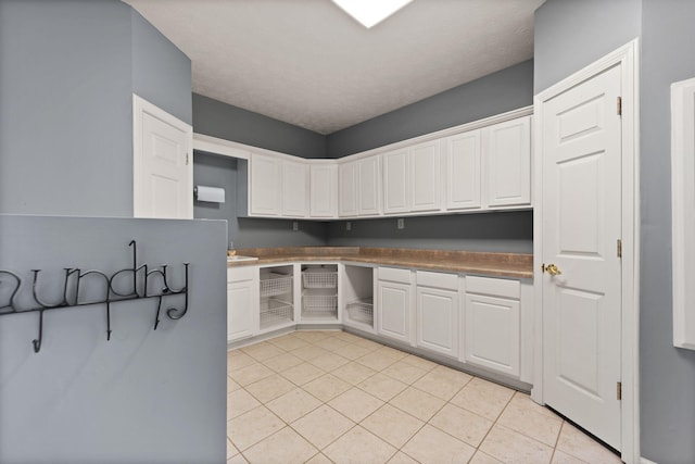 kitchen with white cabinetry, a textured ceiling, and light tile patterned floors