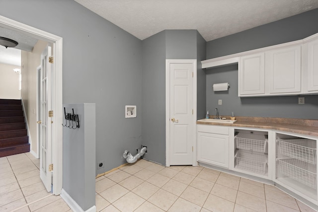 washroom with light tile patterned floors, sink, cabinets, washer hookup, and hookup for an electric dryer