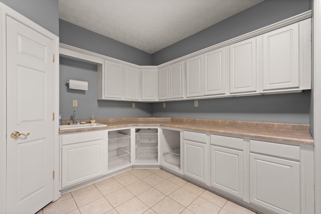 laundry area featuring light tile patterned flooring, sink, and a textured ceiling