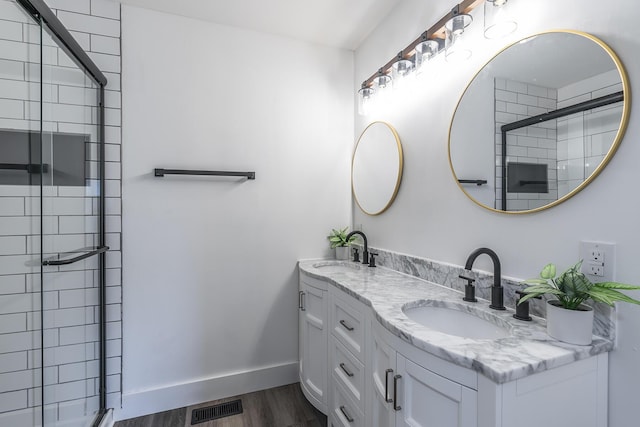 bathroom with wood-type flooring, a shower with shower door, and vanity