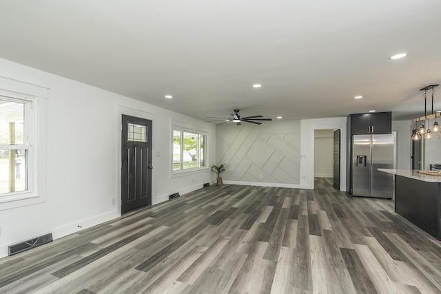 unfurnished living room featuring dark wood-type flooring and ceiling fan