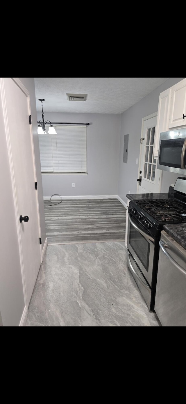 kitchen with electric panel, visible vents, baseboards, appliances with stainless steel finishes, and white cabinetry