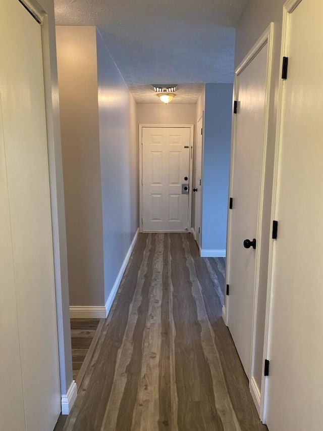 corridor with dark wood-style floors and baseboards