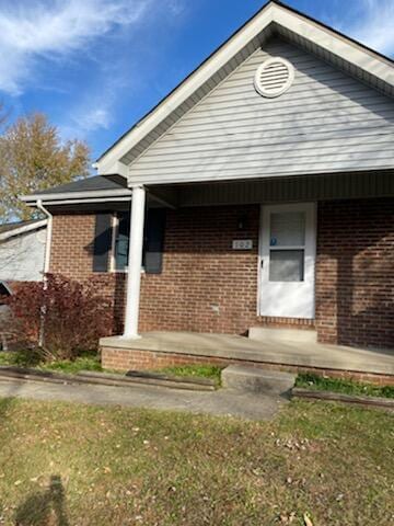 entrance to property featuring covered porch and brick siding