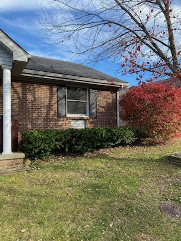 view of side of home with brick siding and a lawn