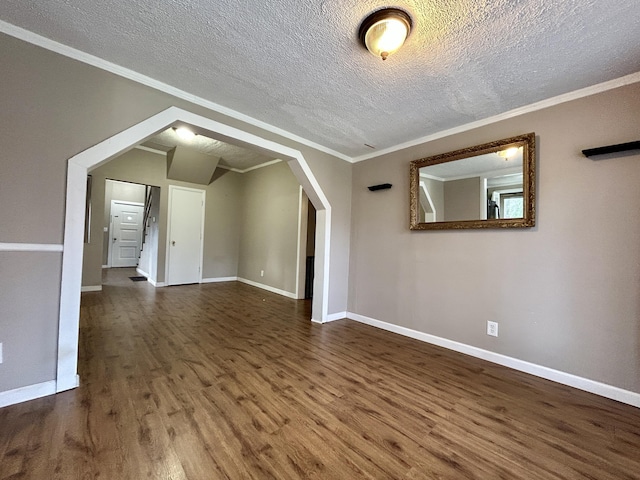 interior space featuring dark wood-type flooring, ornamental molding, and a textured ceiling