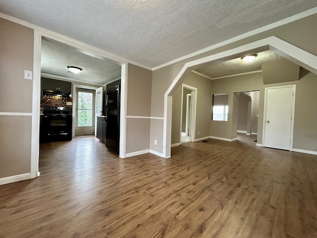 unfurnished living room featuring crown molding, dark wood-type flooring, and a textured ceiling