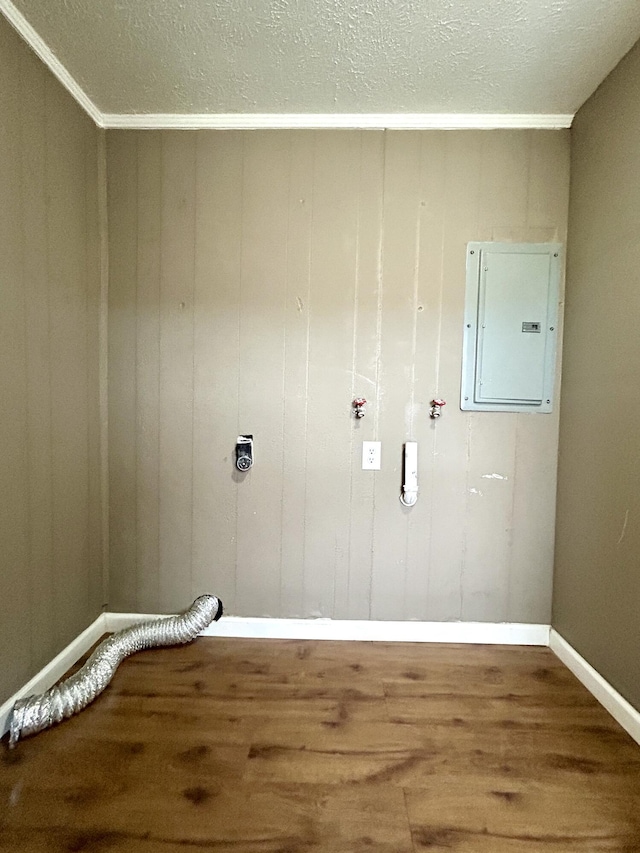 laundry area featuring electric dryer hookup, hardwood / wood-style floors, electric panel, ornamental molding, and wood walls