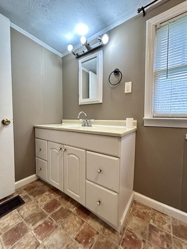 bathroom with vanity, crown molding, and a textured ceiling