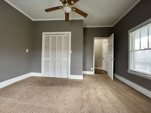 unfurnished bedroom featuring crown molding, carpet, a closet, ceiling fan, and multiple windows