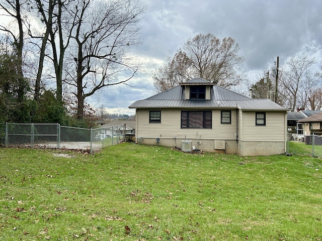 rear view of property featuring cooling unit and a yard