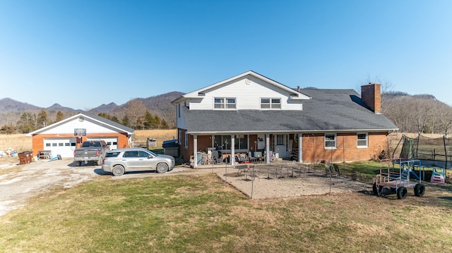 view of front of property featuring covered porch, a trampoline, a garage, a mountain view, and a front yard