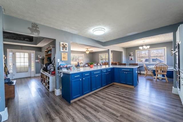 kitchen featuring blue cabinets, plenty of natural light, dark hardwood / wood-style flooring, and kitchen peninsula