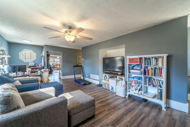 living room with a textured ceiling, dark wood-type flooring, and ceiling fan