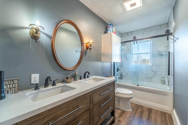 full bathroom with shower / bath combination with glass door, vanity, wood-type flooring, a textured ceiling, and toilet