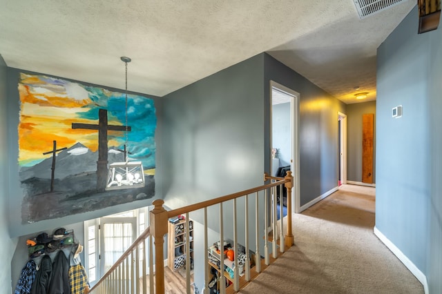 hallway with light colored carpet and a textured ceiling