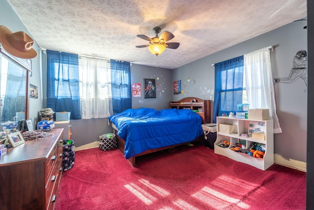 bedroom featuring multiple windows, carpet floors, a textured ceiling, and ceiling fan