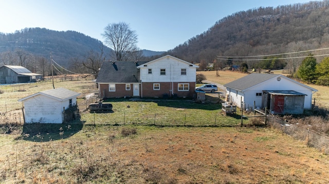 back of property featuring a rural view, a mountain view, and a yard