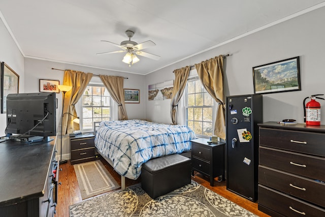 bedroom with crown molding, dark hardwood / wood-style floors, and ceiling fan