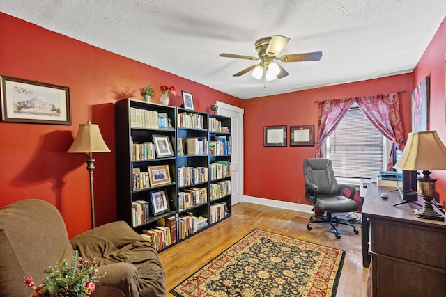 office space with ceiling fan, a textured ceiling, and light wood-type flooring