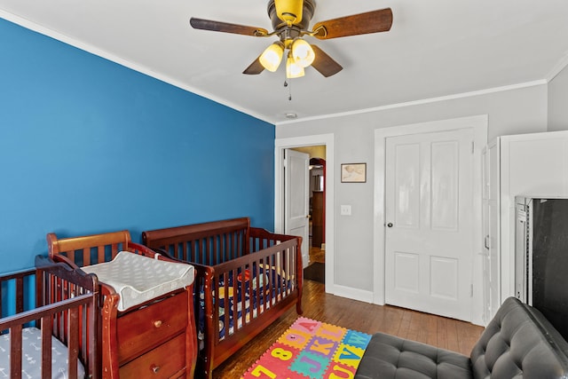 bedroom featuring hardwood / wood-style floors, ornamental molding, and ceiling fan