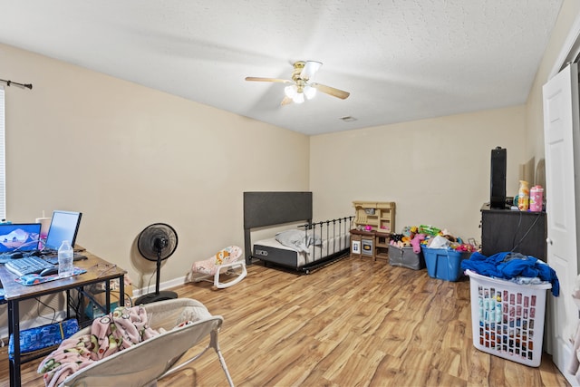 bedroom with a textured ceiling, ceiling fan, and light hardwood / wood-style flooring