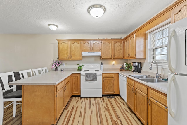 kitchen featuring sink, white appliances, light hardwood / wood-style floors, a kitchen bar, and kitchen peninsula