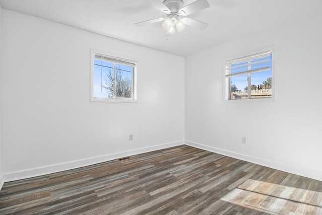 empty room featuring plenty of natural light, dark wood-type flooring, and ceiling fan