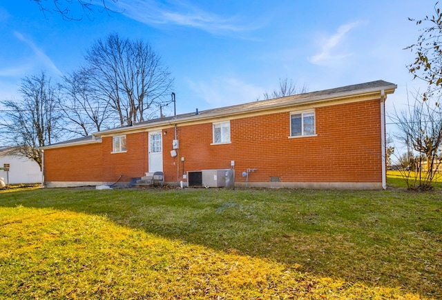 rear view of house with central AC and a yard