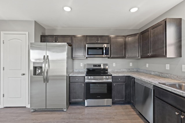 kitchen with stainless steel appliances, light hardwood / wood-style floors, and dark brown cabinets