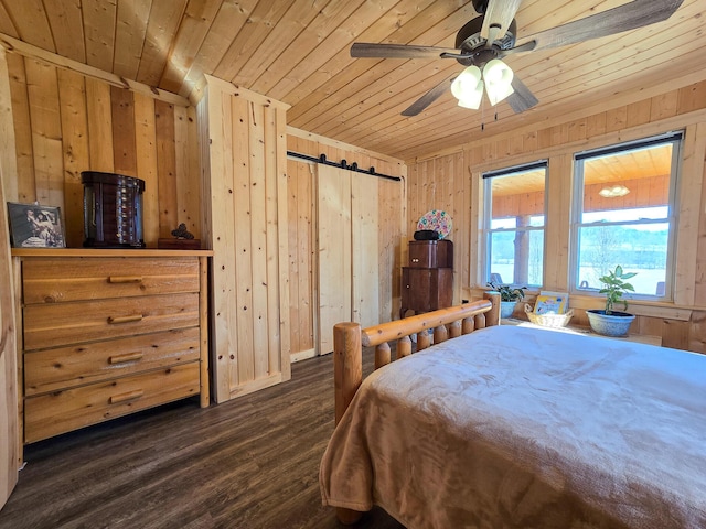 bedroom with wood walls, wooden ceiling, dark hardwood / wood-style flooring, ceiling fan, and a barn door