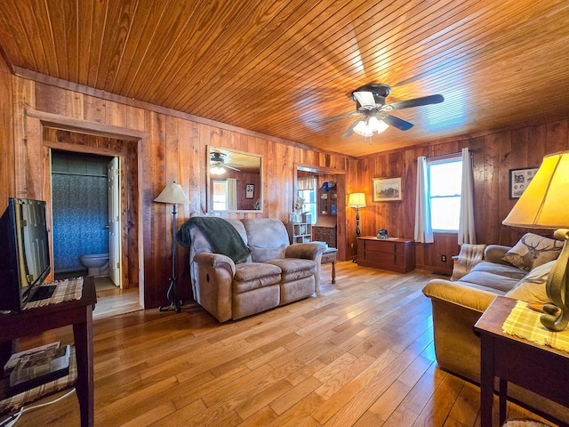 living room with wood ceiling, ceiling fan, wooden walls, and light hardwood / wood-style floors