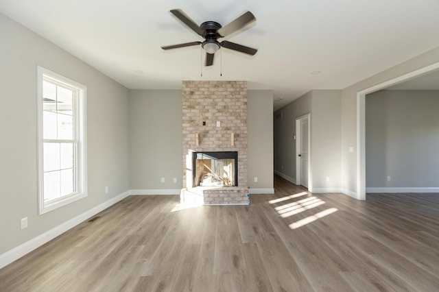 unfurnished living room featuring a fireplace, light hardwood / wood-style flooring, and ceiling fan