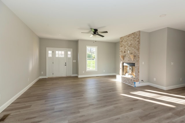 unfurnished living room with ceiling fan, wood-type flooring, and a fireplace