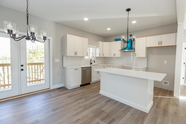 kitchen featuring dishwasher, sink, white cabinets, a center island, and light wood-type flooring