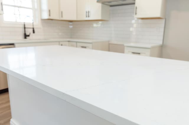 kitchen featuring sink, white cabinetry, tasteful backsplash, light stone counters, and hardwood / wood-style floors