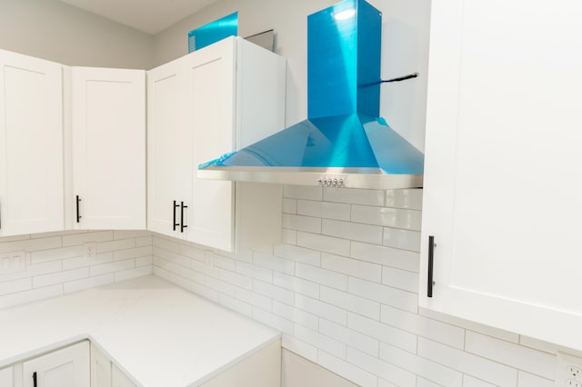 kitchen with white cabinetry, decorative backsplash, and wall chimney range hood