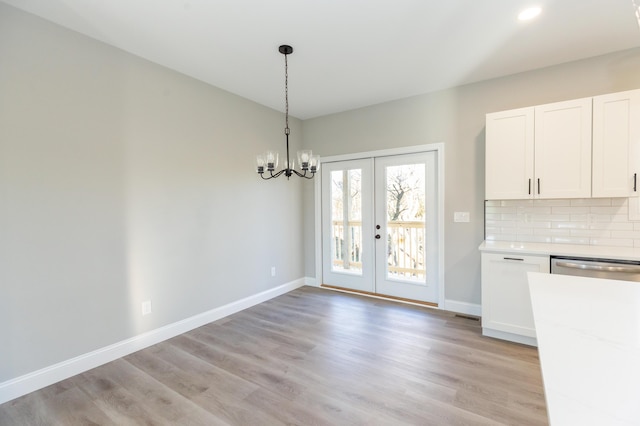 unfurnished dining area with light hardwood / wood-style flooring, a notable chandelier, and french doors