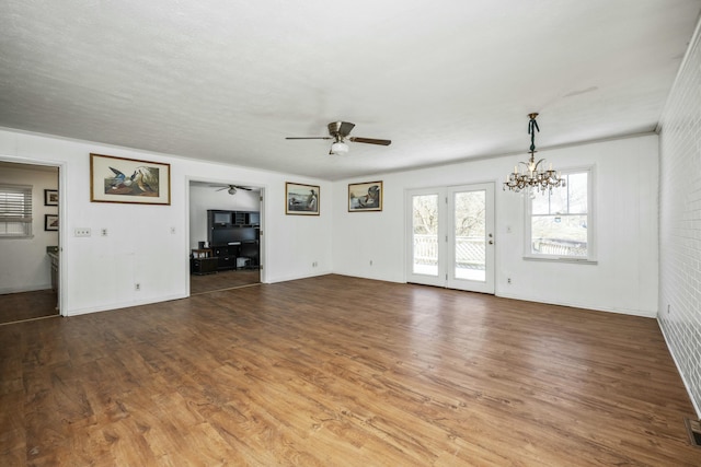 unfurnished living room with ceiling fan with notable chandelier, wood finished floors, and visible vents