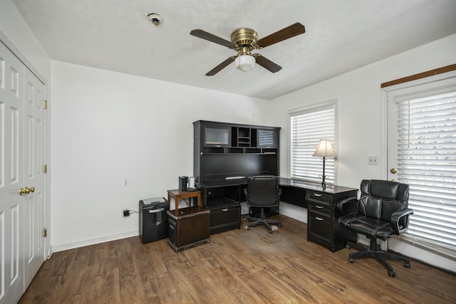 home office featuring dark wood finished floors, a ceiling fan, and baseboards