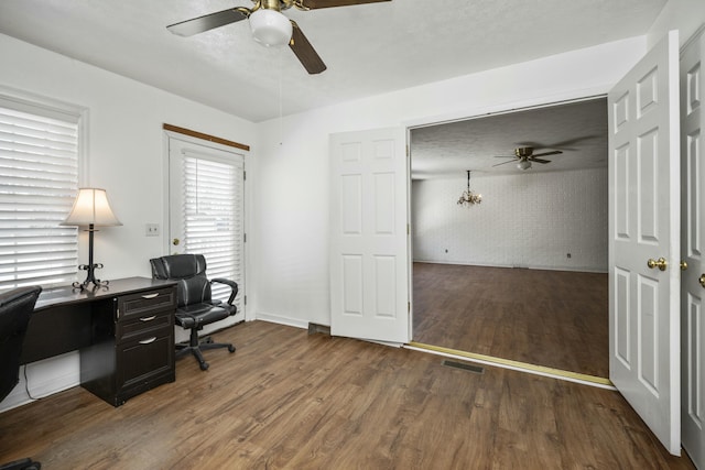 home office featuring a ceiling fan, dark wood-style flooring, visible vents, and brick wall