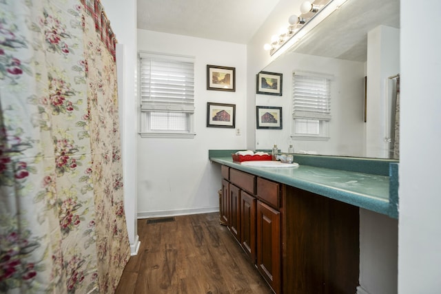 full bath with visible vents, vanity, baseboards, and wood finished floors