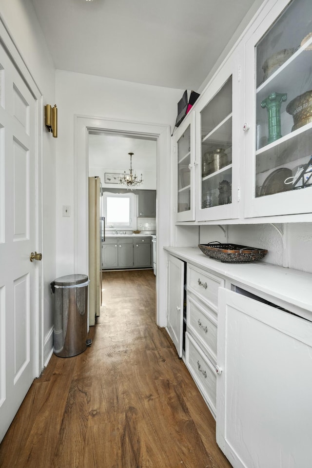 bar featuring baseboards, dark wood finished floors, freestanding refrigerator, and an inviting chandelier